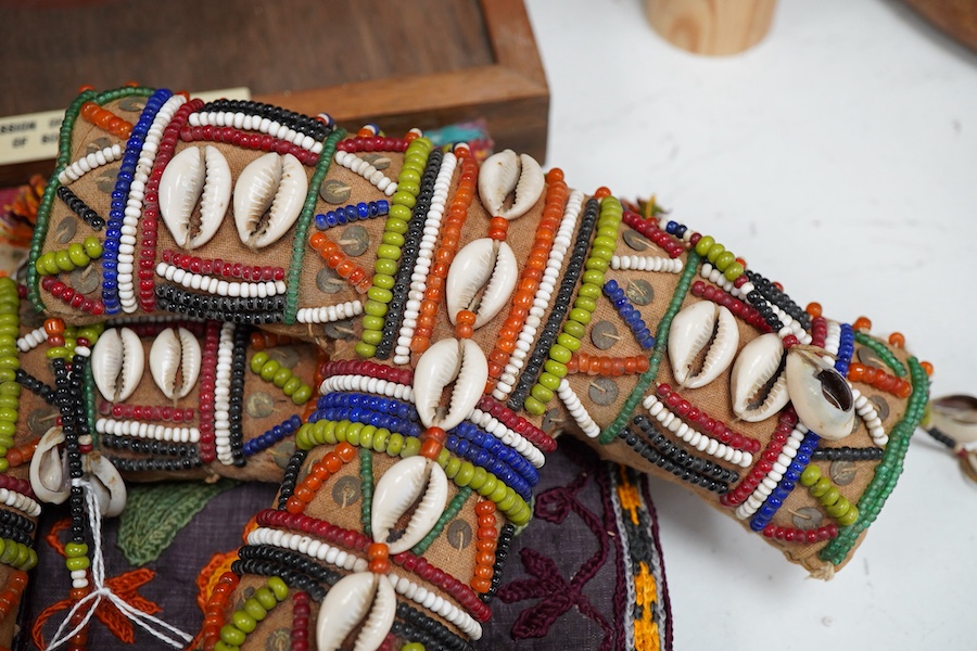19th and 20th century textiles: An Indian mirrored and patchwork bag, a smaller embroidered bag, an ‘arrow’ shaped mirrored panel and two Omani shell and beaded ‘anchor’ shaped hangings, ‘arrow’ hanging 45cm long and two